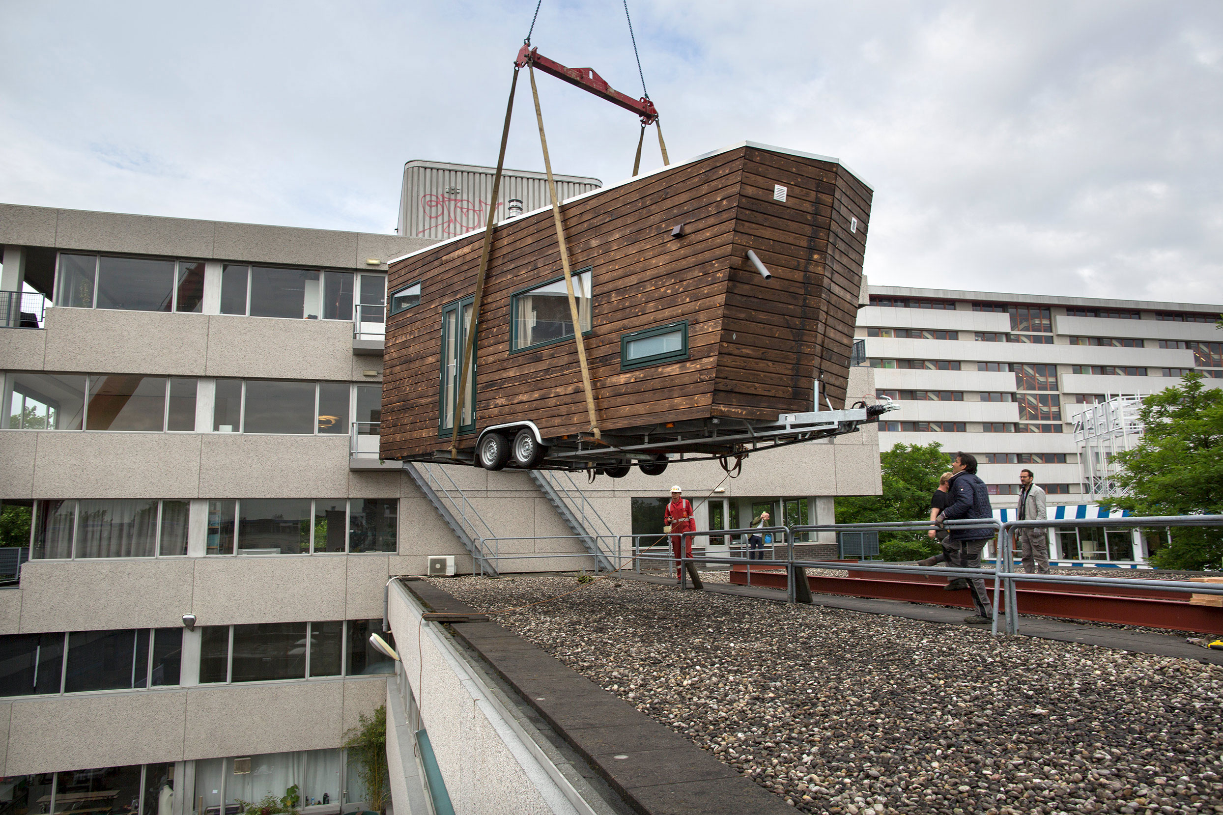 Livraison par grue d'une tiny-house (petite maison bien pensée et bien exécutée) sur un toit de Rotterdam, dans le cadre d'un projet de création de logements de l'association Dakdorpen.