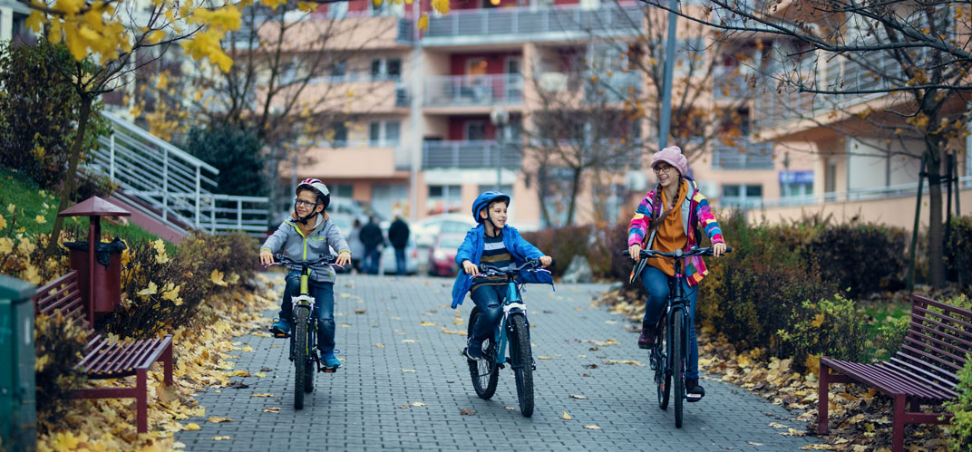 Des enfants à vélos dans un quartier urbain résidentiel et arboré