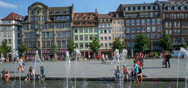 Place du centre-ville à Rennes ou Strasbourg avec des fontaines et miroirs d'eau où se réunissent les habitants.