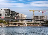 Projet de logements des maires : vue d'immeubles en construction au bord d'un fleuve.