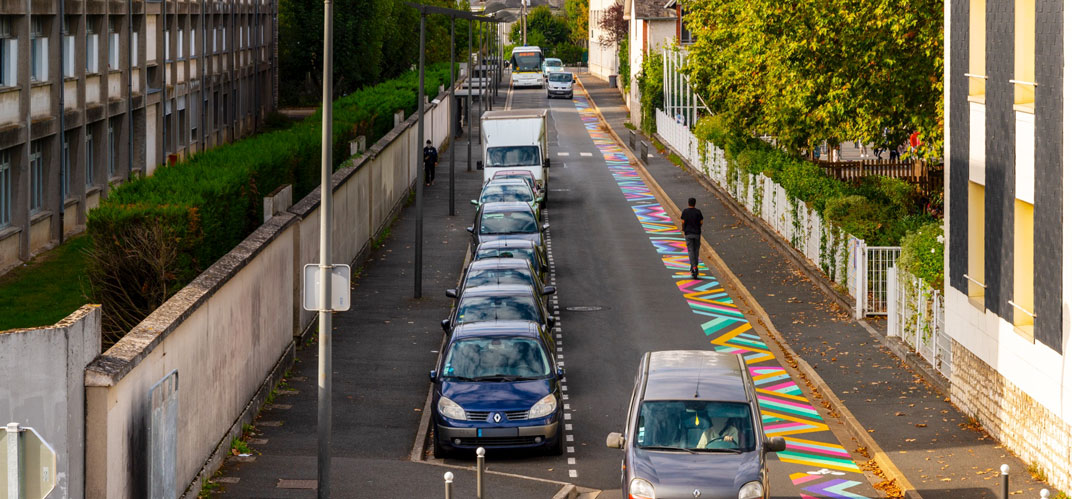 Art urbain : une piste cyclable peinte comme une fresque graphique et colorée.