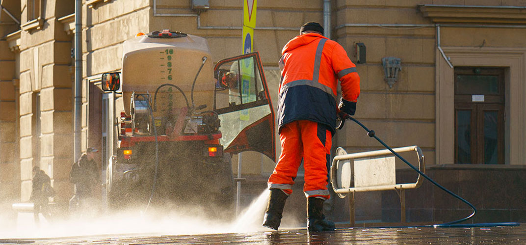 Eaux usées : un technicien de propreté des espaces publics nettoyant une rue au jet d'eau.
