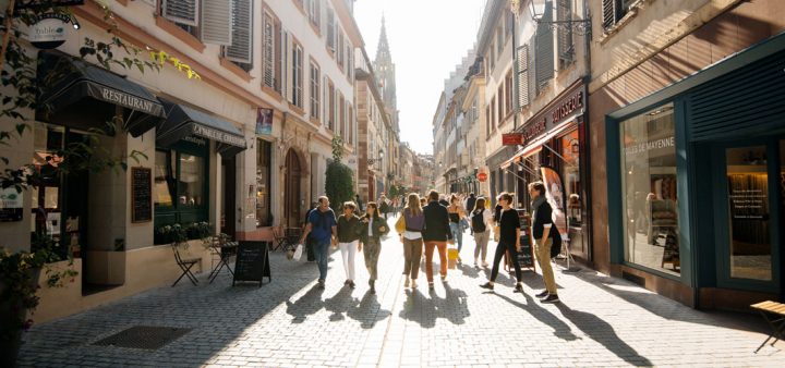 Promeneurs dans une rue bordées de commerces d'un centre-ville.