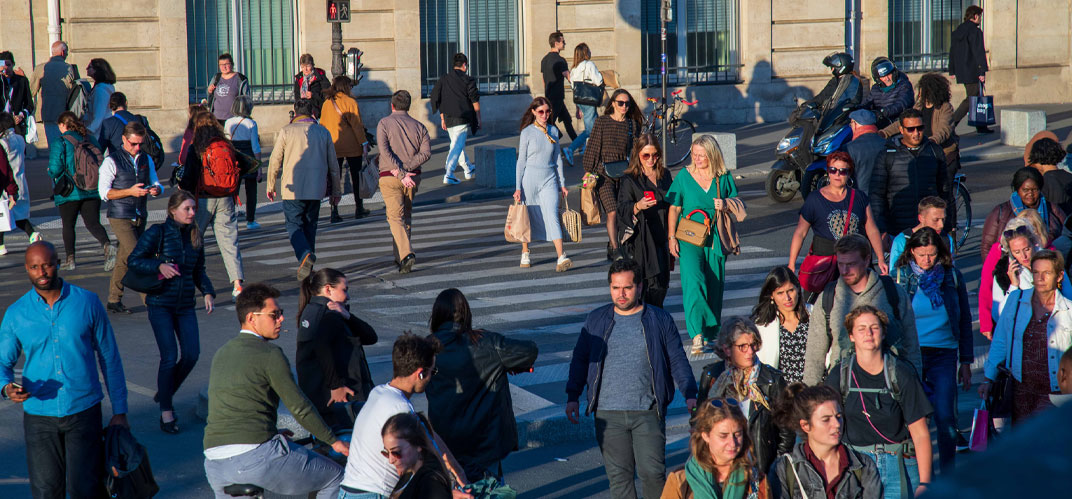 Décohabitation : des passant·e·s se croisant sur un passage piéton en fin d'après-midi.