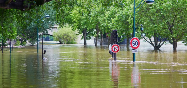 Risques climatiques : une ville inondée, les panneaux de signalisation et les cimes des arbres émergeant à peine de l'eau. ©IStock