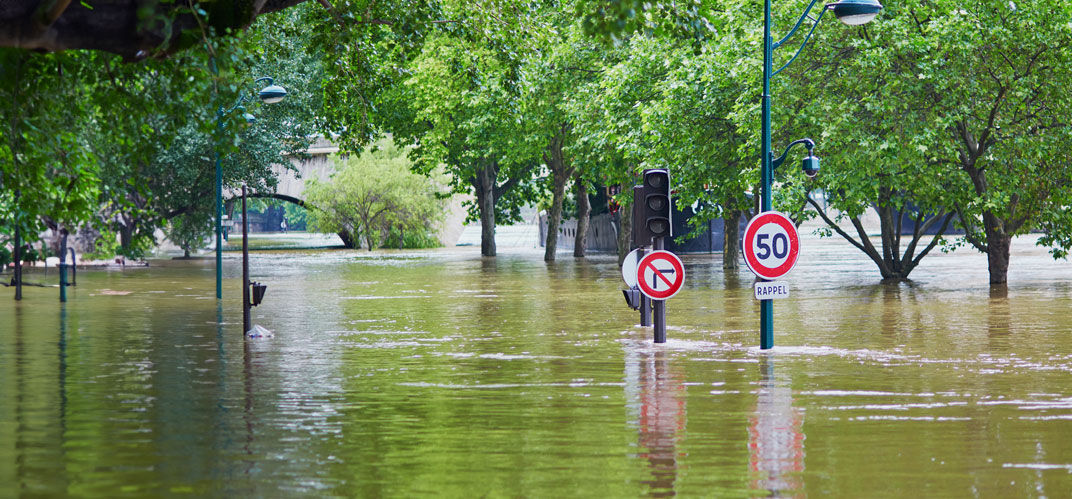 Risques climatiques : une ville inondée, les panneaux de signalisation et les cimes des arbres émergeant à peine de l'eau. ©IStock