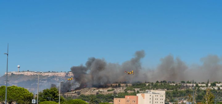 Risque climatique pour les villes : un canadair survolant un incendie dans l'arrière pays d'une ville française.