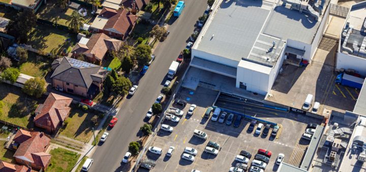 Vue aérienne d'une entrée de ville avec zone commerciale et quartier pavillonnaire.