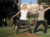 Un couple de seniors pratiquant le yoga sur la pelouse d'un parc de centre-ville.
