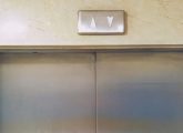 Pannes d’ascenseur : plan serré sur les portes d'une cabine depuis un hall d'immeuble.