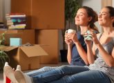 Deux jeunes femmes assises au milieu de cartons, en plein emménagement.